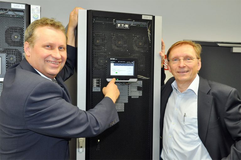 Josef Fruehwirth und Walter Cerny stehen links und rechts von einer Eaton UV-Anlage 93PM