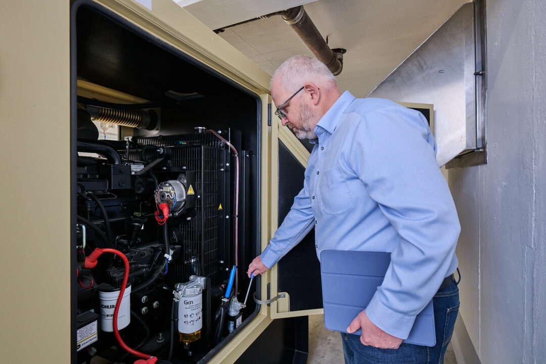 Bruno Durst, responsible for building technology and technical project management at Volksbank Raiffeisenbank Nordoberpfalz eG, stands in front of an open emergency power generator