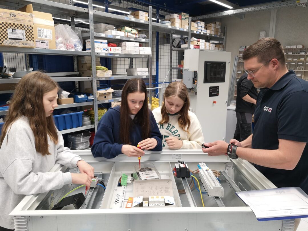 Schuelerinnen der dritten Klasse der neuen Mittelschule Weitra bauen mit Gottfried Stoeger, stellvertretendem Leiter der Technikabteilung bei EPS, an einem Verteilerkasten mit