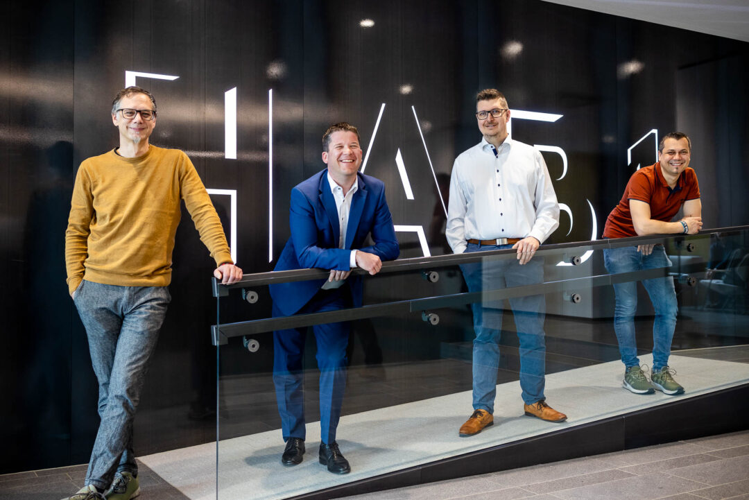Claus Hofer, Deputy Head of IT at HABAU GROUP, Peter Reisinger, Managing Director of EPS Electric Power Systems GmbH, Gerald Froschauer, Head of IT at HABAU GROUP, and Paul Muehlbächler, IT Services Infrastructure Server at HABAU GROUP, are standing in the entrance area of HABAU in Perg.